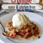 Close up view of a serving of gluten free rhubarb crumble, topped with vanilla ice cream, on a small white dessert plate with a spoon and more crumble in the background. White text overlays with red and black text for Pinterest.