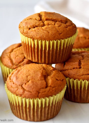 Close up view of one gluten free pumpkin muffin stacked on other pumpkin muffins.