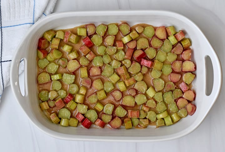 Overhead view of rhubarb filling in a white 9x13-inch baking pan on counter.
