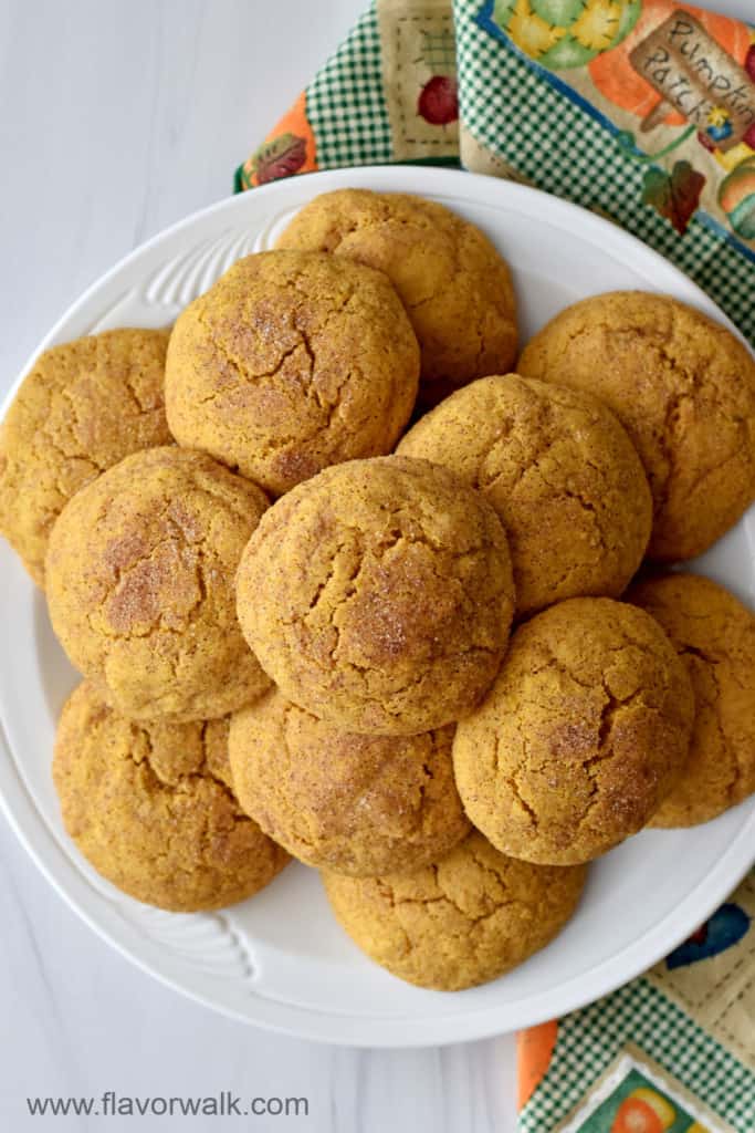 Overhead view of a stack of gluten free pumpkin snickerdoodles on a round white plate with a multi-colored cloth napkin on the right.