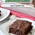 A slice of gluten free chocolate zucchini cake on small white plate with more cake in the background and text overlay near top for Pinterest.