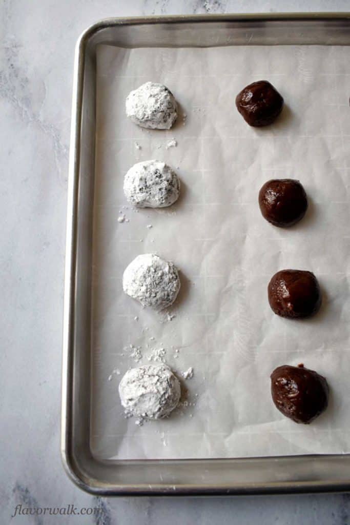 Close up view of 8 gluten free chocolate crinkle dough balls. The 4 dough balls on the left are coated in powdered sugar and the 4 dough balls on the right are not.