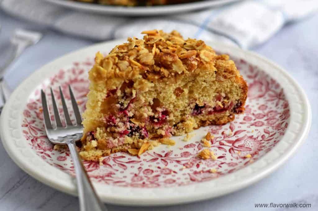 Close up view of a slice of gluten free cranberry cake and a fork on a white and pink floral plate.