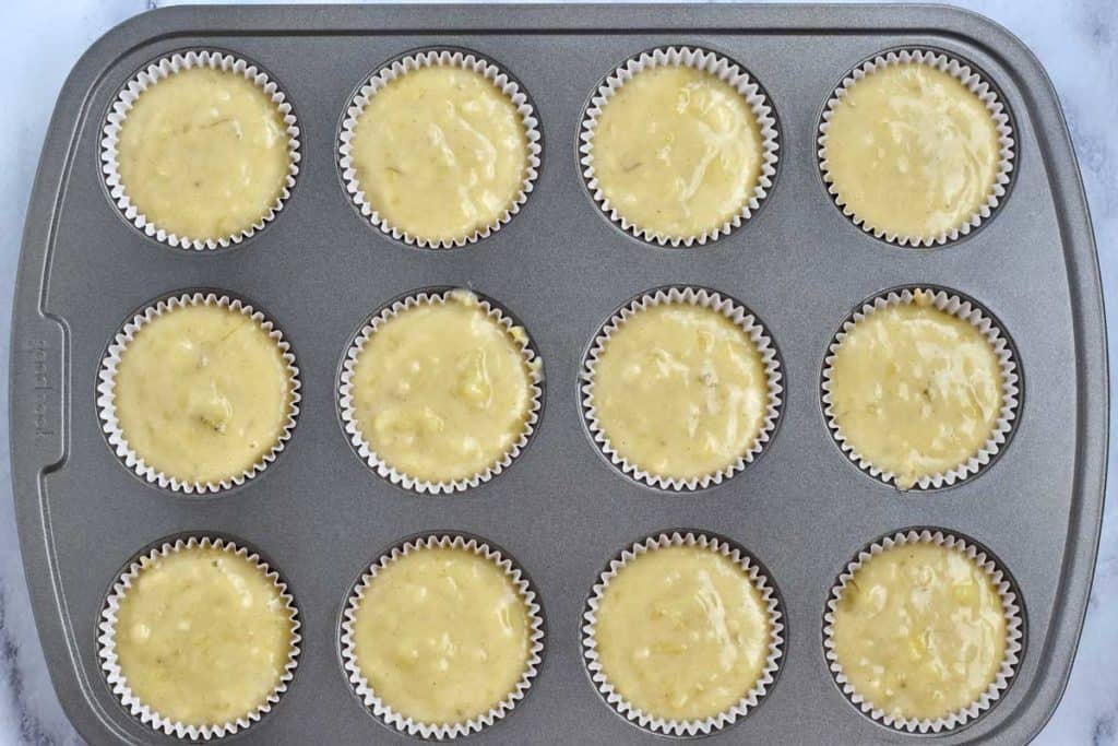 Overhead view of muffin tin filled with gluten free banana muffin batter.