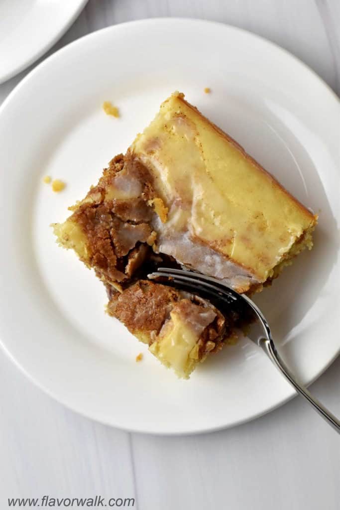 One slice of easy cinnamon roll cake and fork on white dessert plate.