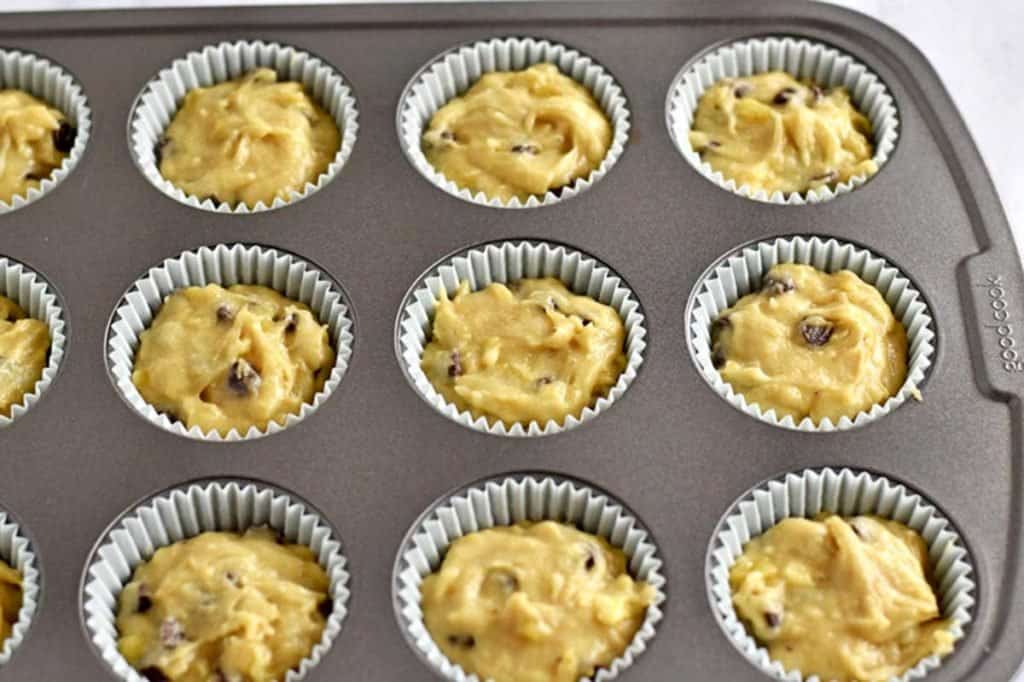 Lined muffin pan filled with gluten free chocolate chip banana muffin batter.