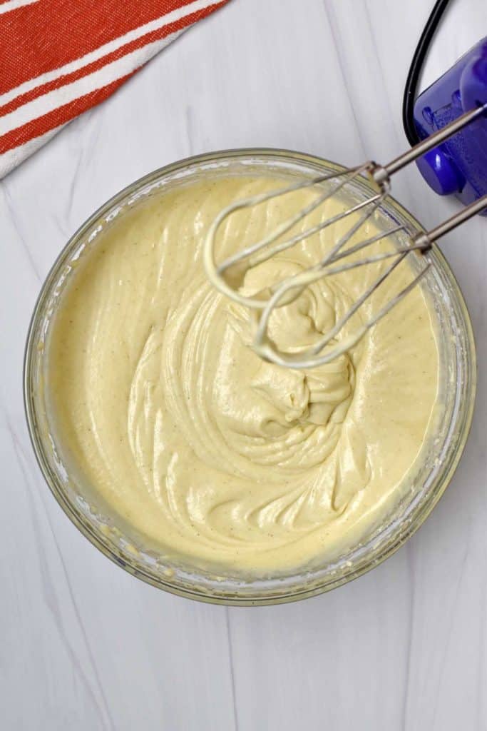 Glass mixing bowl with melted butter beaten into cinnamon roll cake batter.