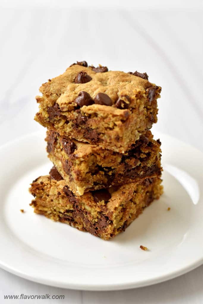A stack of three gluten free oatmeal chocolate chip bars on a white dessert plate.