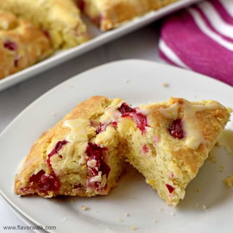 One scone on a small white dessert plate with more scones in the background.
