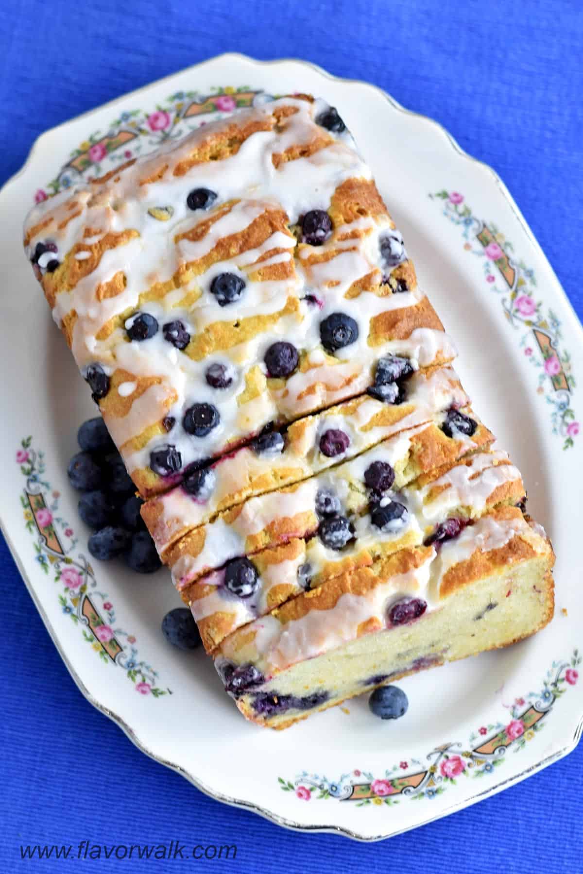 Overhead view of a sliced loaf of gluten free lemon blueberry bread on a serving plater.