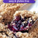 Large spoon scooping out a serving of gluten free blueberry crisp with text overlay, "Blueberry Crisp, Easy & Gluten Free."
