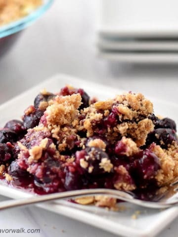 Gluten free blueberry crisp and fork on small white plate.