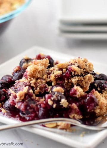 Gluten free blueberry crisp and fork on small white plate.