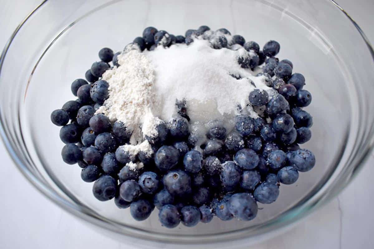 Gluten free blueberry crisp filling ingredients in glass mixing bowl.