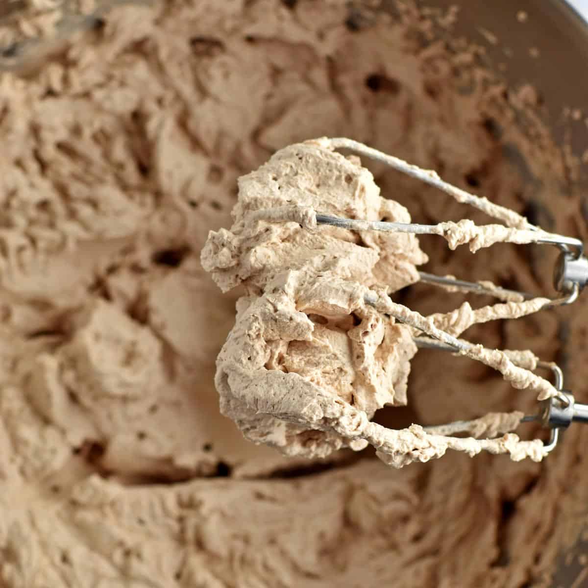 A mixing bowl and beaters filled with the chocolate whipped cream for making old-fashioned chocolate icebox cake.
