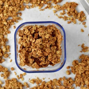 Cinnamon granola in a small container surrounded by more granola.