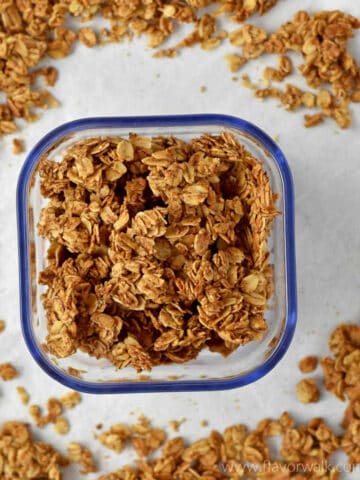 Cinnamon granola in a small container surrounded by more granola.