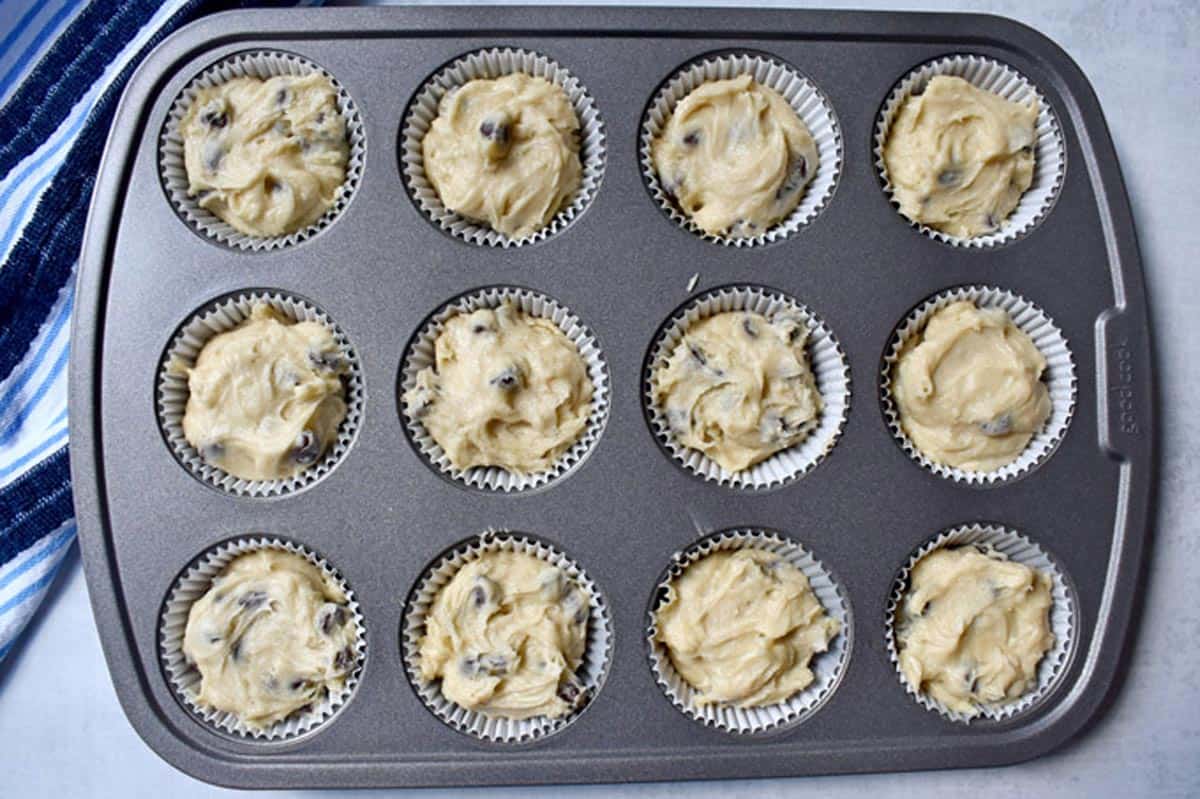 Chocolate chip muffin batter in lined muffin tin.