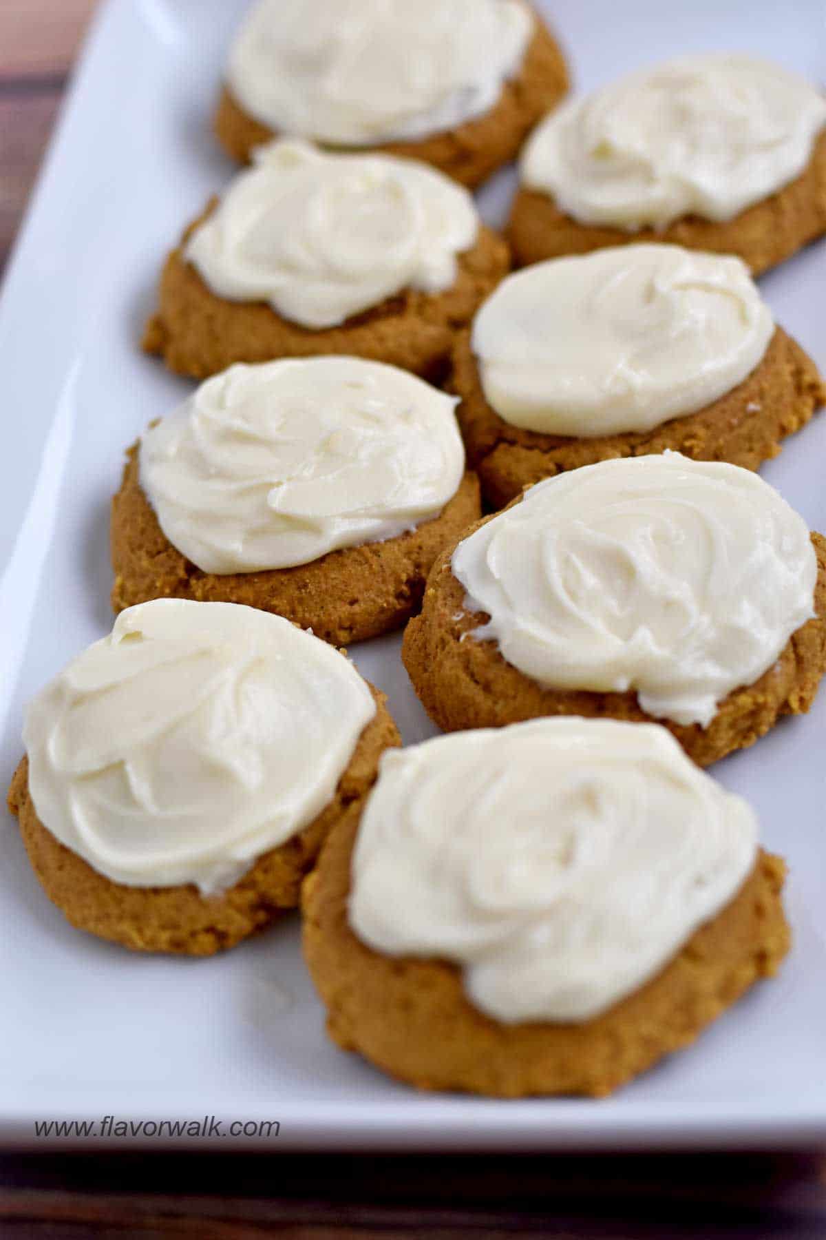 Gluten free pumpkin cookies with cream cheese frosting on white platter.
