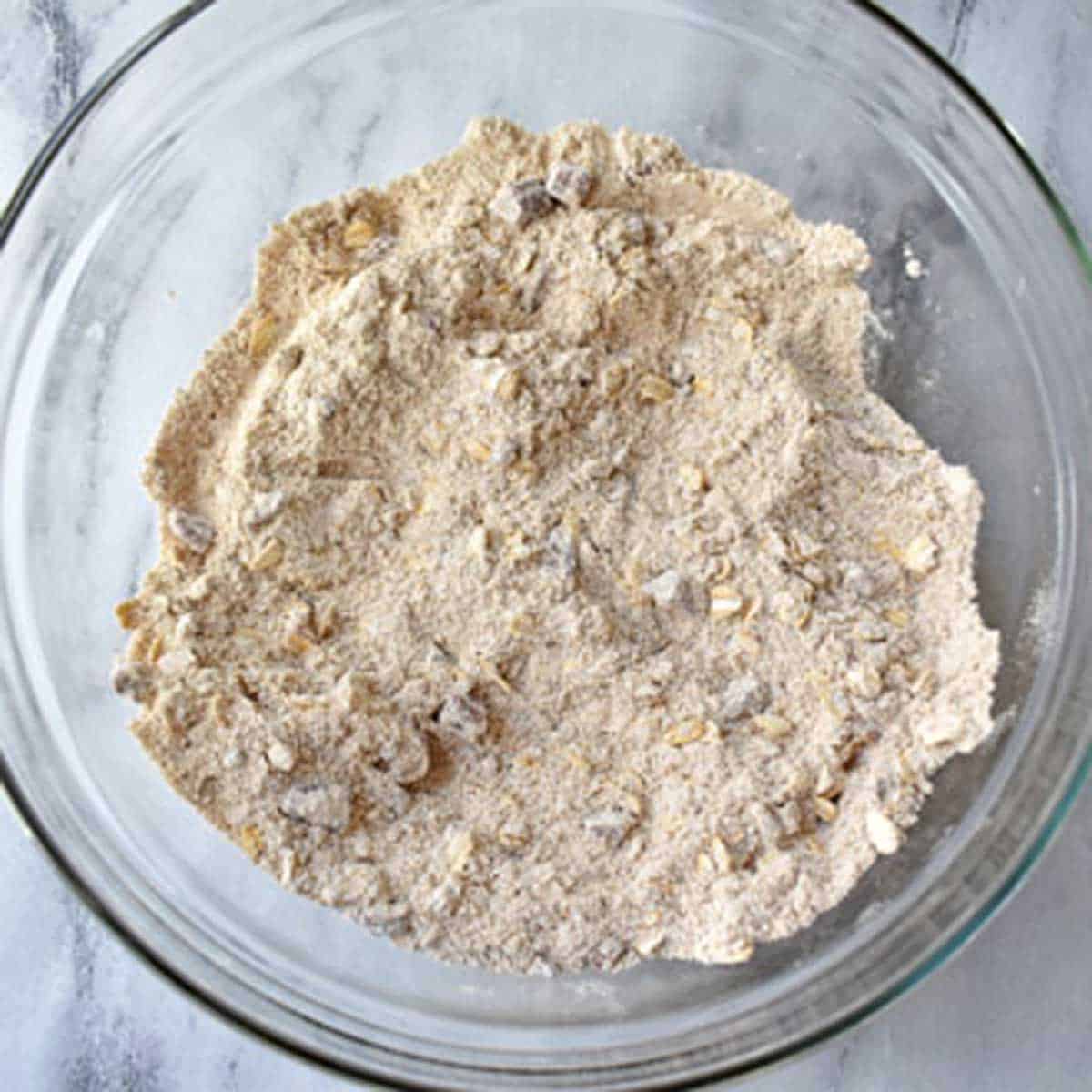 Gluten free flour, brown sugar, gluten free oats, salt, chopped pecans, and spices whisked together in a glass mixing bowl.