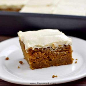 A gluten free pumpkin bar on a white plate with the remaining bars in the background.