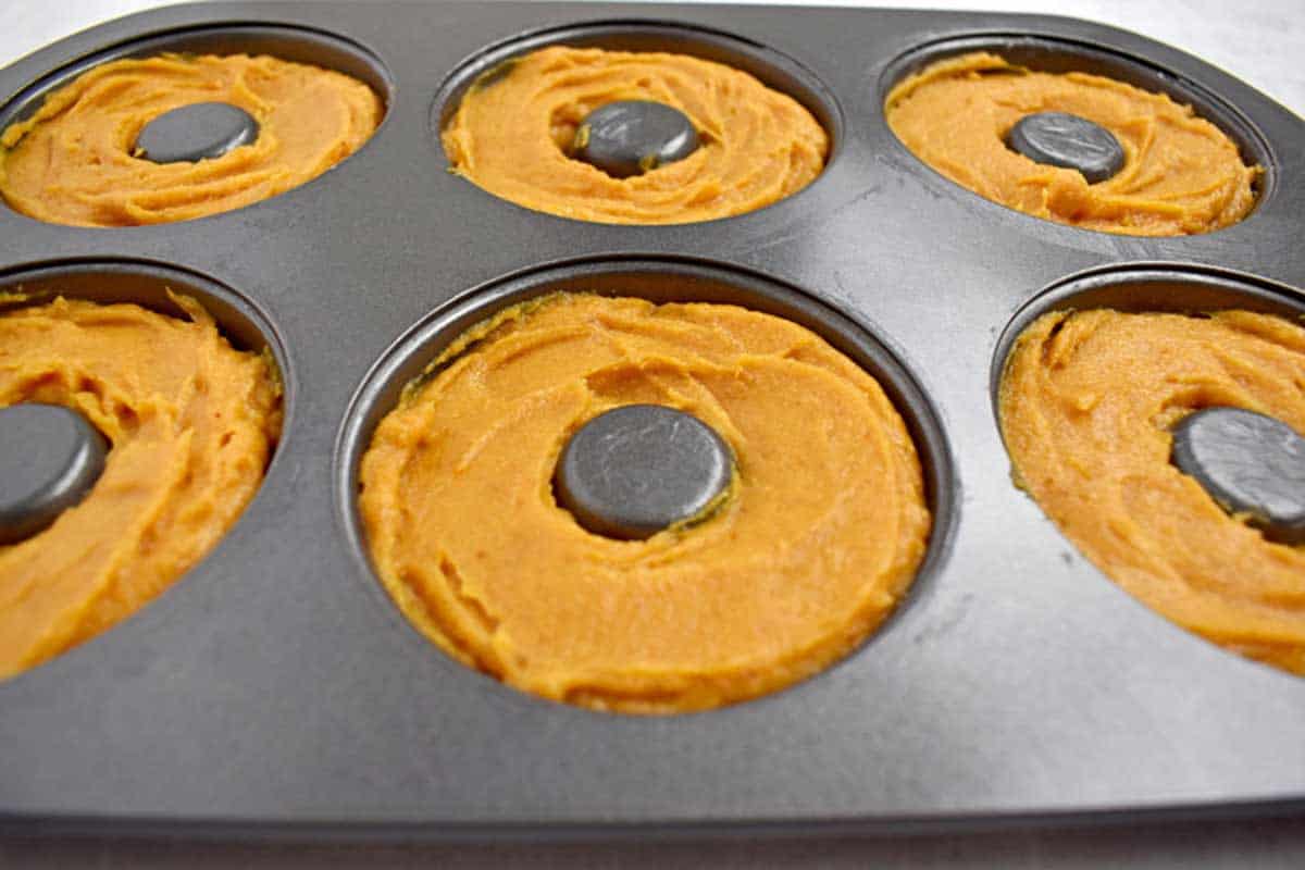Donut pan filled with batter for making pumpkin donuts.