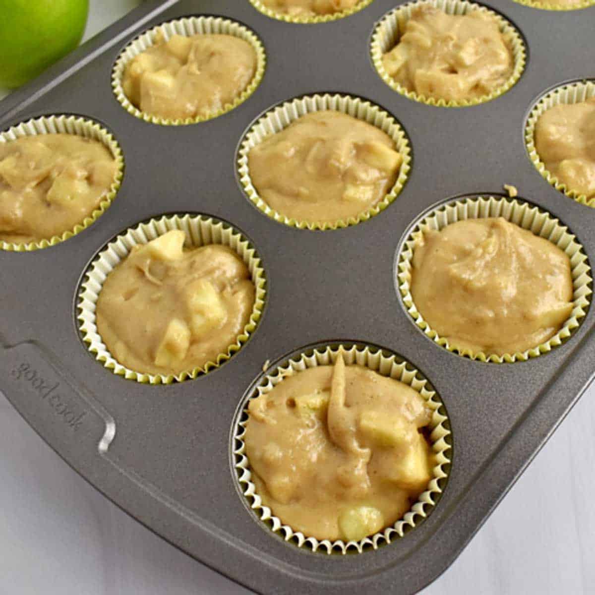 Batter for gluten free apple muffins in lined muffin pan.