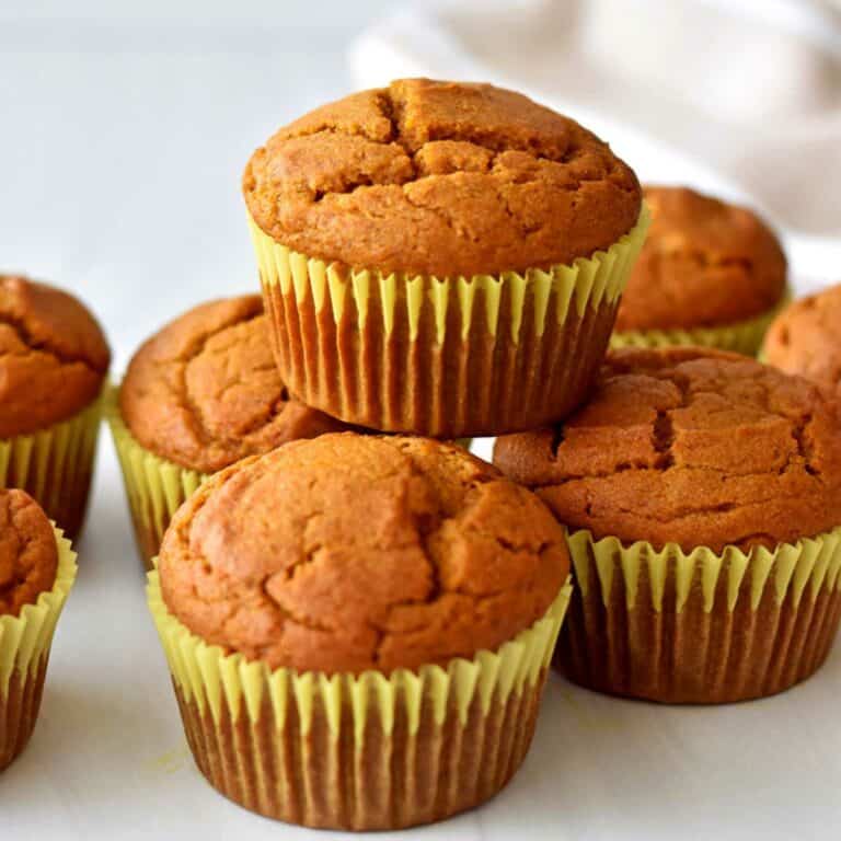 Gluten free pumpkin muffins stacked on a kitchen counter.