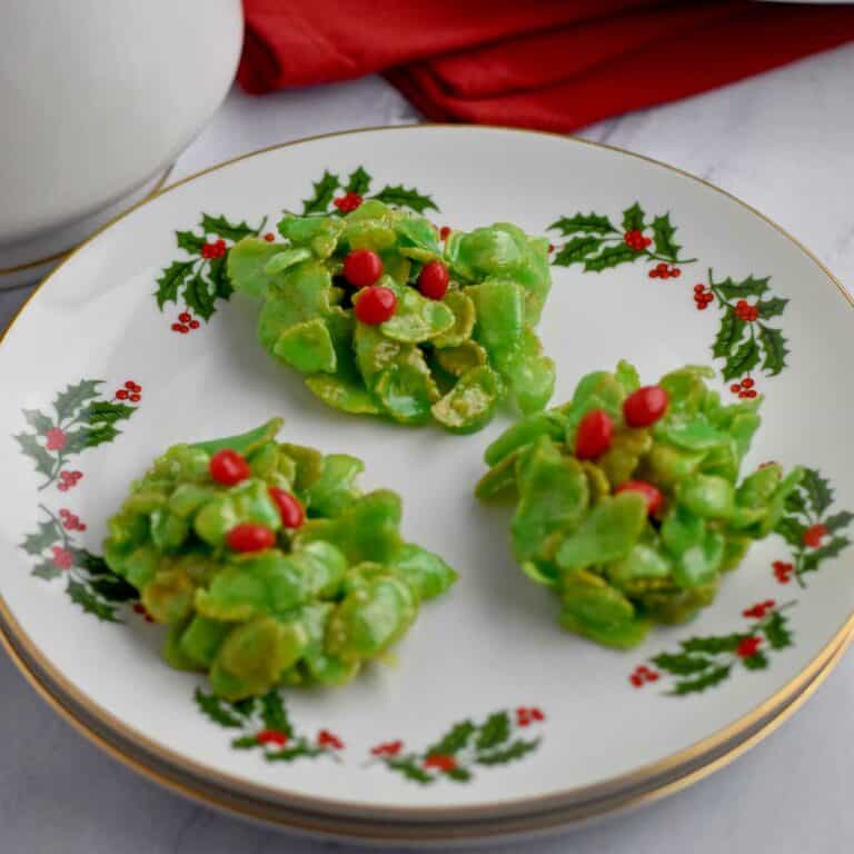 Three holly cookies on a small round plate.
