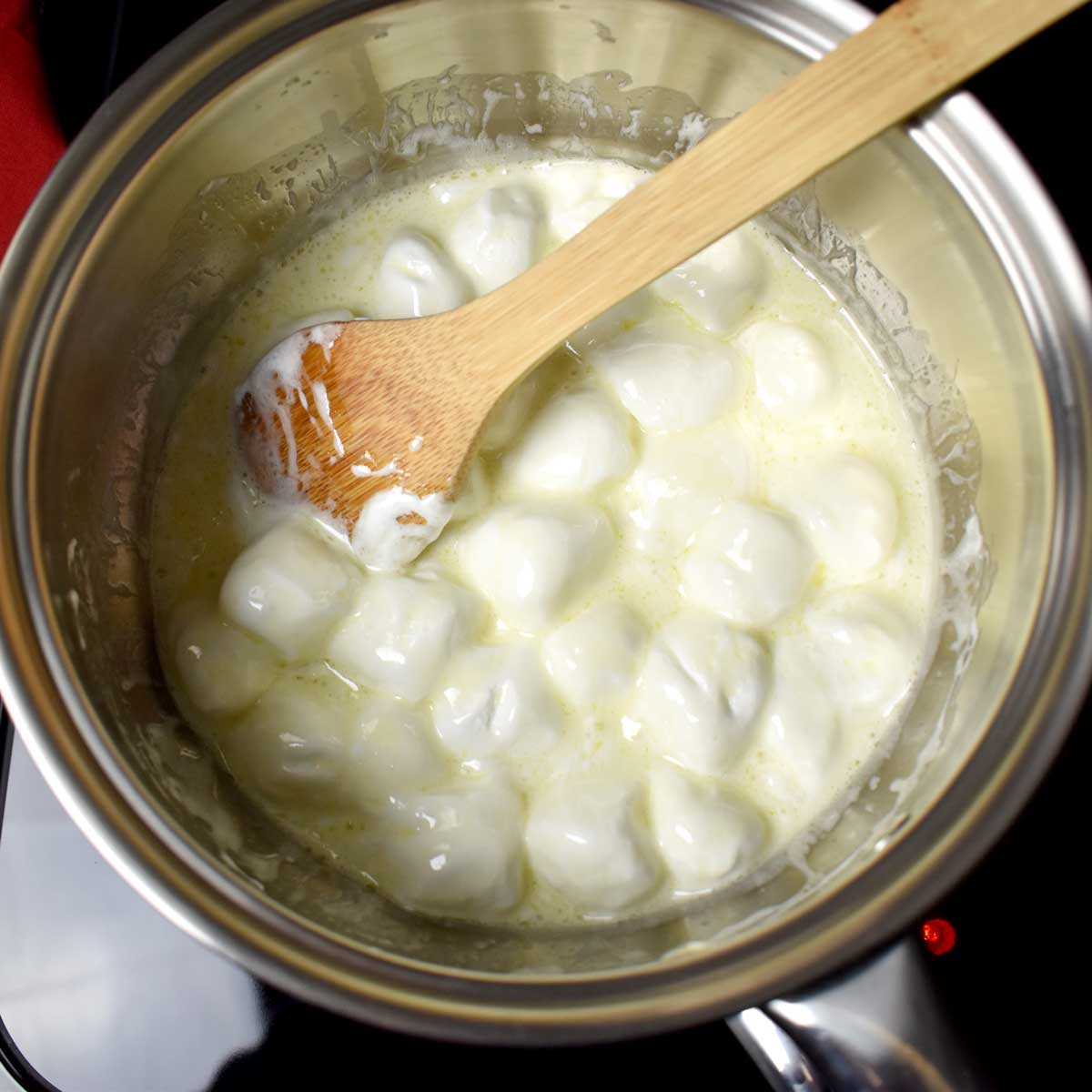 Melting butter, marshmallows, and a wooden spoon in a large saucepan.