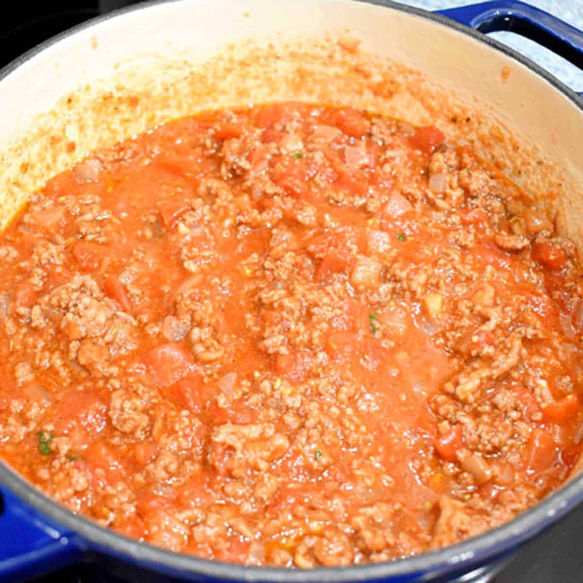 Meat sauce for making gluten free lasagna in a blue Dutch oven.