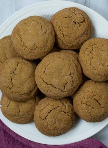 Gluten free molasses cookies piled on a round white serving plate.