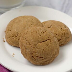 Three gluten free molasses cookies on a round white plate.