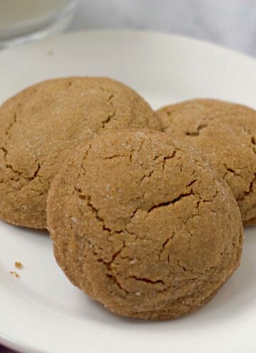Three gluten free molasses cookies on a round white plate.