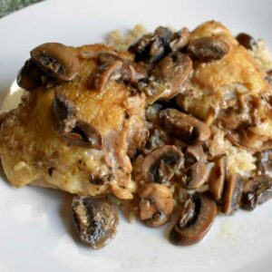 Close up view of chicken marsala on white plate.