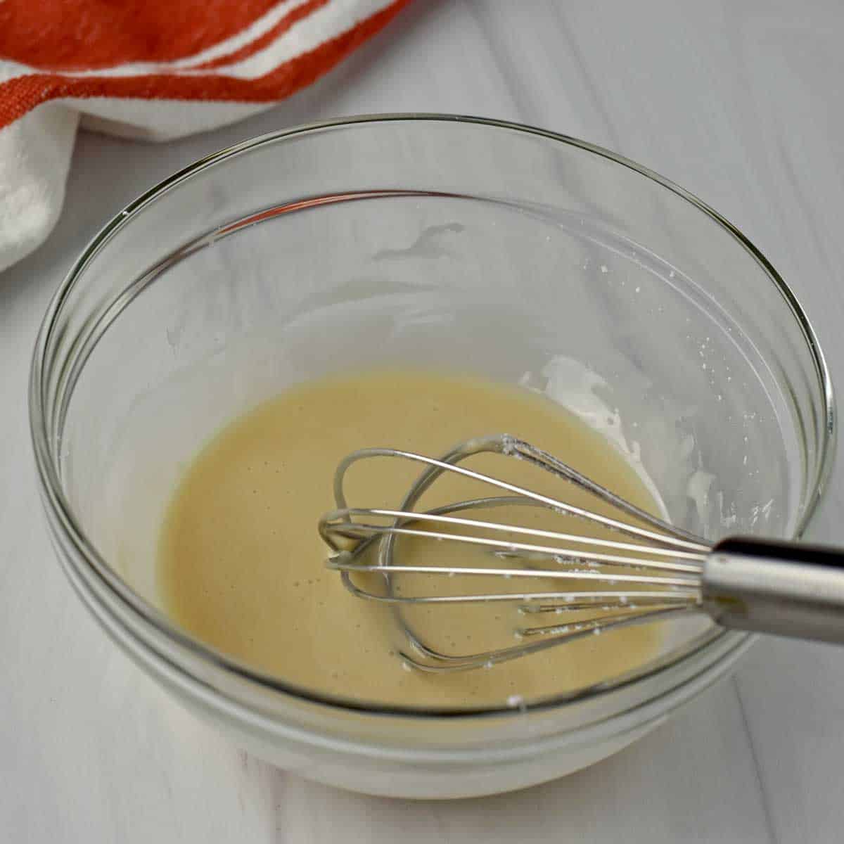 Ingredients for apple fritter glaze whisked together with wire whisk in small glass mixing bowl.