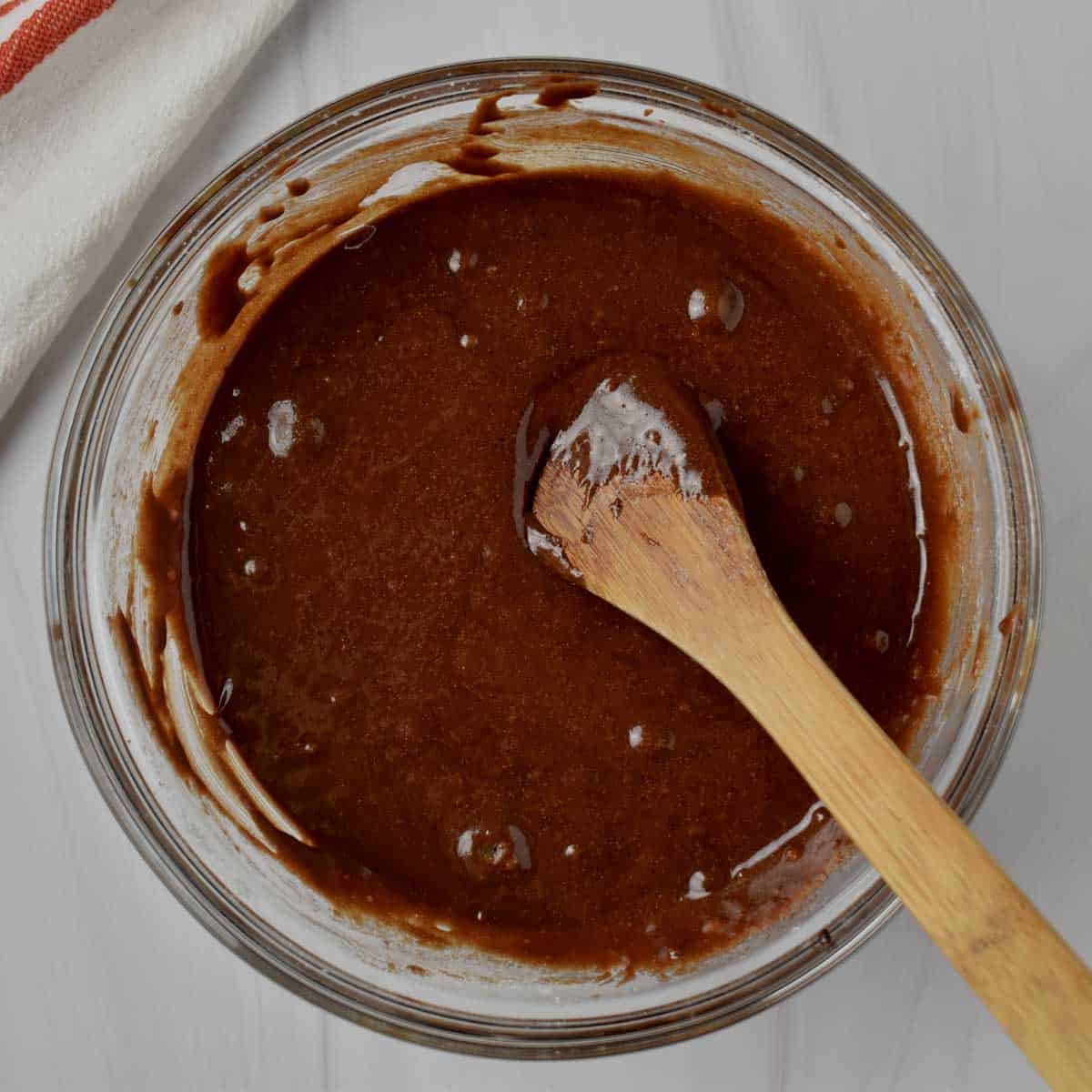 Rocky road brownie batter and wooden spoon in glass mixing bowl.