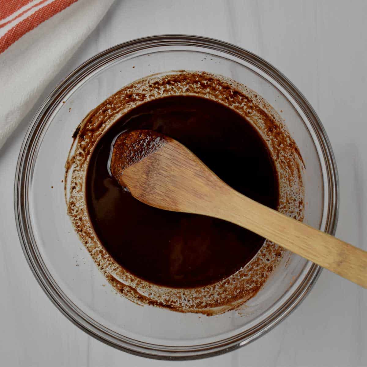 Melted butter and unsweetened cocoa powder stirred together in glass mixing bowl.
