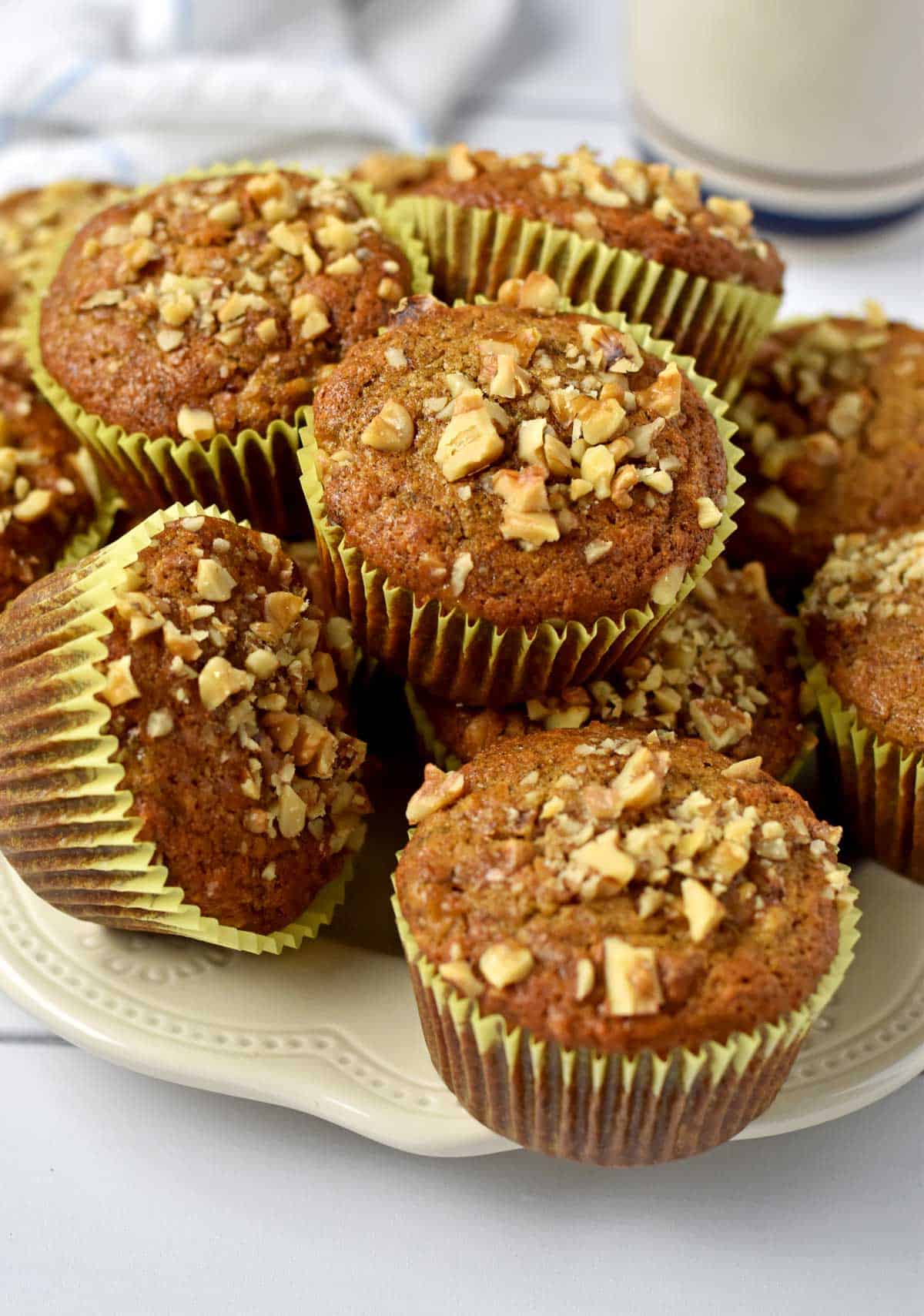 Gluten free banana nut muffins stacked on a serving plate.