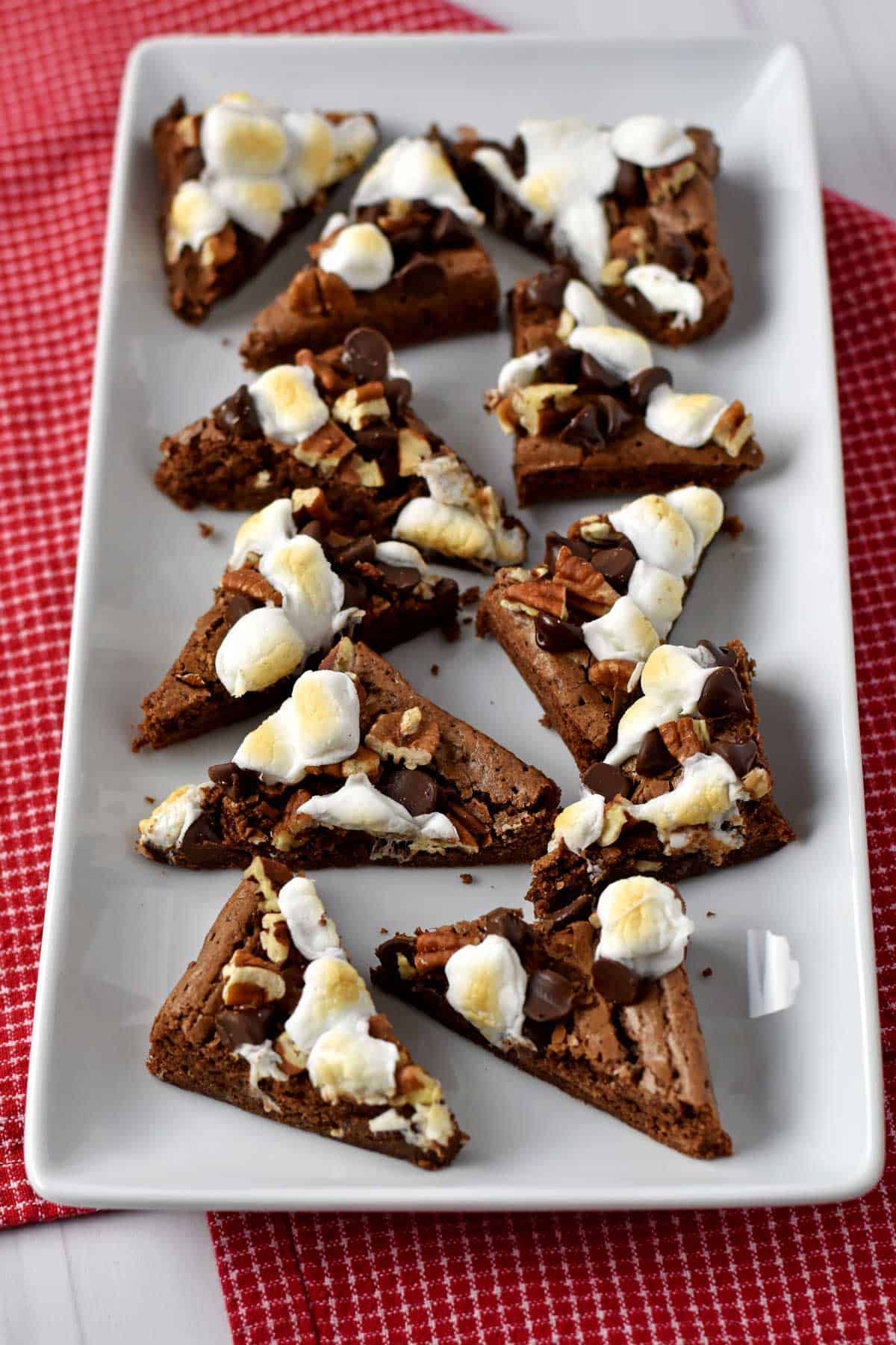 A platter of gf rocky road brownies on a red and white checked kitchen towel.