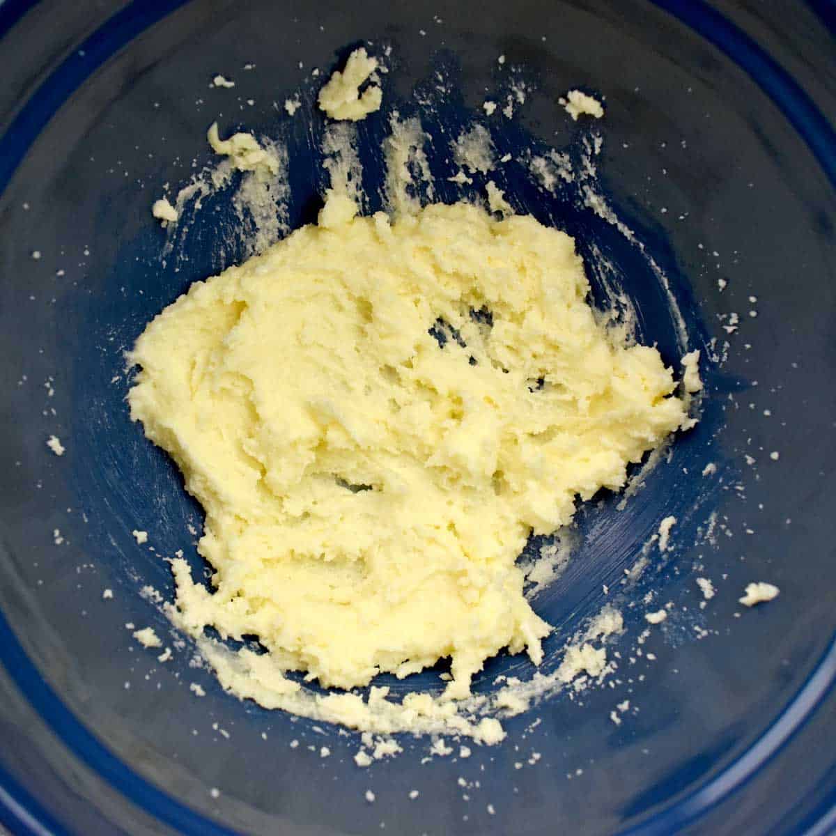 Butter and sugar creamed together in blue mixing bowl.