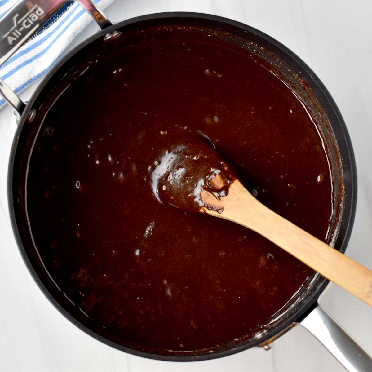 Brownie batter and wooden spoon in saucepan.