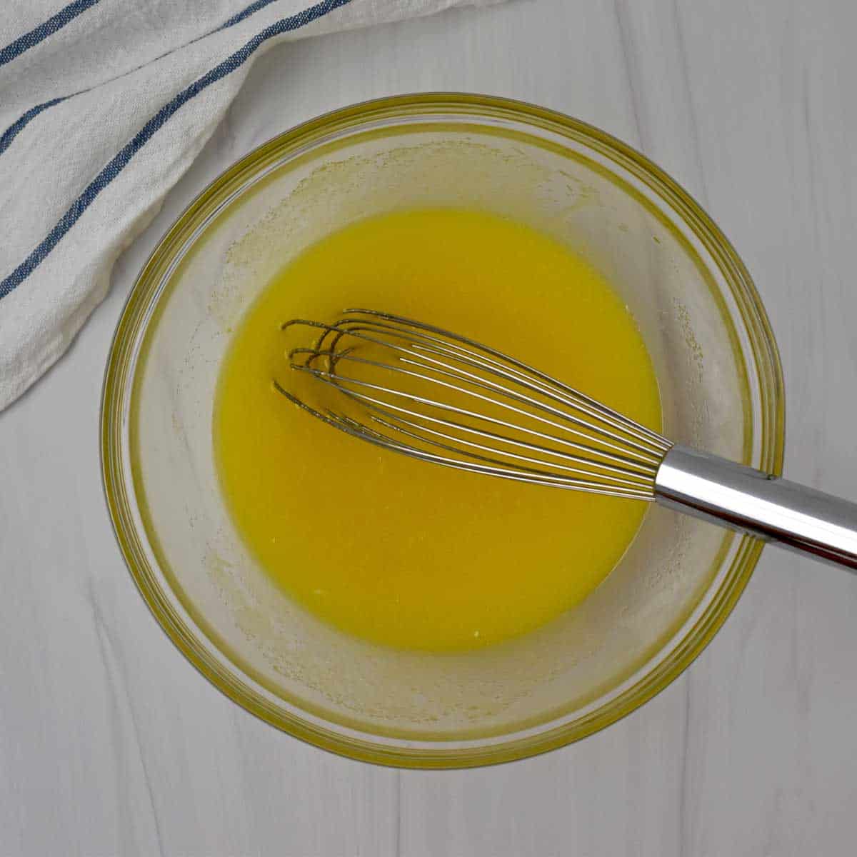 Sugar, vegetable oil, and eggs whisked together in glass mixing bowl.